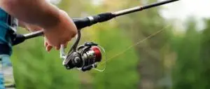 A luxury fly fishing reel and rod resting on a polished wooden surface.
