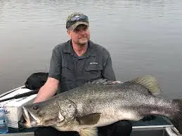 An angler sport fishing from the rocky shores of the Nile River in Murchison Falls National Park
