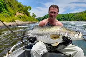Angler holding a giant Nile Perch caught during a luxury fishing safari in Uganda