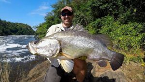 Fisherman celebrating after landing a trophy-sized Nile perch on Lake Victoria Fishing Safari Top Uganda Fishing Charters